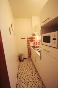 uma pequena cozinha com um micro-ondas e um fogão em Haus Dithmarschen Wohnung 2 em Büsum