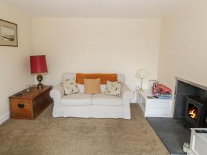 a living room with a white couch and a fireplace at 7 Cummertrees in Annan
