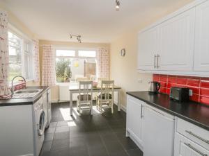 a kitchen with white cabinets and a table with chairs at 7 Cummertrees in Annan