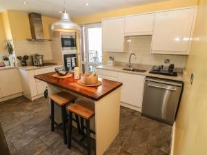 a kitchen with white cabinets and a wooden counter top at Gwenallt in Pwllheli