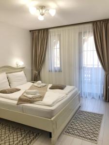 una camera da letto con un grande letto bianco e una finestra di Pensiunea ARMONIA a Văleni