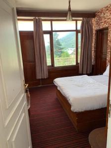 sypialnia z łóżkiem i dużym oknem w obiekcie vella Mrina Group of hotel Manali w mieście Manāli