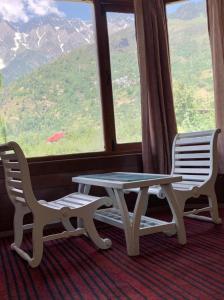 stół i dwa krzesła przed oknem w obiekcie vella Mrina Group of hotel Manali w mieście Manāli