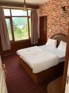 a bedroom with a large bed with a brick wall at vella Mrina Group of hotel Manali in Manāli