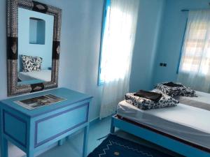 Dormitorio azul con cama y espejo en Room in Guest room - Pretty room in villa Lair De La Mer, in Sidi Kaouki, en Sidi Kaouki