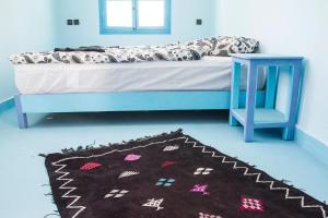 - une chambre avec un lit, une table bleue et un tapis dans l'établissement Room in Guest room - Pretty room in villa Lair De La Mer, in Sidi Kaouki, à Sidi Kaouki