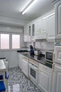 a white kitchen with white cabinets and appliances at Apartamento Muy Amplio, con WiFi y a 12 Minutos del Centro in Gijón