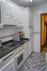 a white kitchen with white cabinets and a microwave at Apartamento Muy Amplio, con WiFi y a 12 Minutos del Centro in Gijón