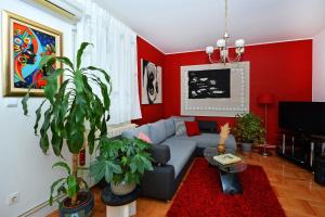 - un salon avec un canapé bleu et des murs rouges dans l'établissement Artsy Apartment, à Klis