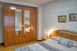 a bedroom with a bed and a wooden cabinet at Apartamento Muy Amplio, con WiFi y a 12 Minutos del Centro in Gijón