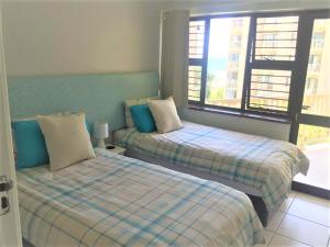 a bedroom with two beds and a window at Umdloti Cabanas 21 Triplex in Umdloti