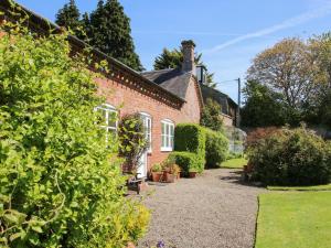 een bakstenen huis met een tuin ervoor bij The Stables in Shrewsbury