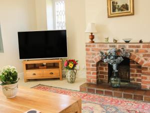 a living room with a tv and a brick fireplace at The Stables in Shrewsbury