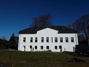 un grand bâtiment blanc avec un toit noir dans l'établissement Ferienwohnung im Palais Rosenlund, à Hürup