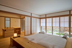 a bedroom with a bed and a desk and windows at Azumi Setoda in Onomichi