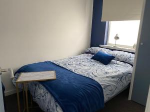 a small bedroom with a bed with a blue comforter at Ugly Duckling, License number FI 00863 P in Fife