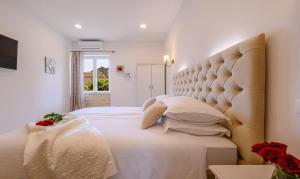 a bedroom with a large white bed with a large headboard at Summer breeze luxury rooms in Split