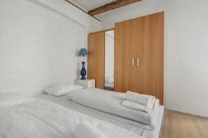 a white bedroom with a large bed and a wooden cabinet at Copenhagen City Apartment with cosy backyard in vibrant area in Copenhagen