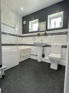 a white bathroom with a sink and a toilet at Bungalow33 Benllech in Benllech +35 photos