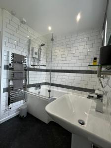 a white bathroom with a sink and a bath tub at Bungalow33 Benllech in Benllech