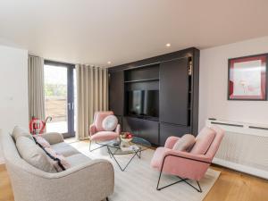 ein Wohnzimmer mit rosa Stühlen und einem TV in der Unterkunft 35 Hope Place in Bath