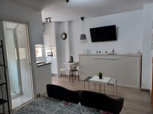 un soggiorno con divano e TV a parete di LA BELLA MALAGUETA a Málaga