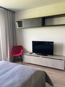 a bedroom with a television and a red chair at Sunset Studio Apartment in Poprad