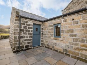 a stone building with a blue door and a patio at Little Esklets in Whitby