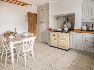 斯基普頓的住宿－Crag View Cottage，厨房配有白色橱柜和桌椅