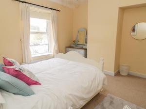 a bedroom with a white bed with a window at Crag View Cottage in Skipton