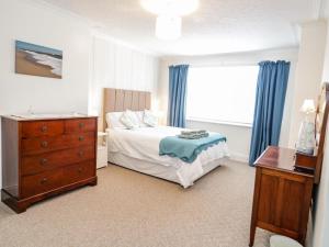 a bedroom with a bed and a dresser and a window at 3 St Davids Place in Llandudno