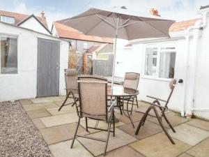 a table and chairs with an umbrella on a patio at 3 St Davids Place in Llandudno