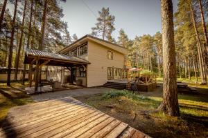 a house with a wooden deck in the woods at Villa Marika Holiday Centre in Alajõe