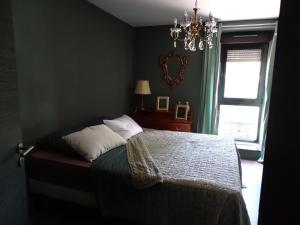 1 dormitorio con cama, lámpara de araña y ventana en BOIS DE CHENES HOUSE en Phalsbourg