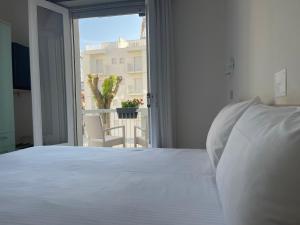 una camera con un letto bianco e una grande finestra di Hotel Athena a Lignano Sabbiadoro