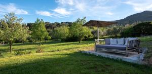 a bench with an umbrella in a field at Il Molino Carlotta House in Porto Ercole