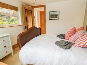 1 dormitorio con 1 cama con sábanas y almohadas blancas en Garden Cottage, en Ilkley