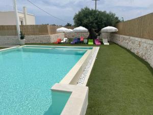 a swimming pool with lounge chairs next to a wall at Tuo Hotel in Polignano a Mare