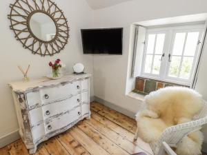 a room with a dresser and a mirror and a chair at Swn yr Afon in Caernarfon