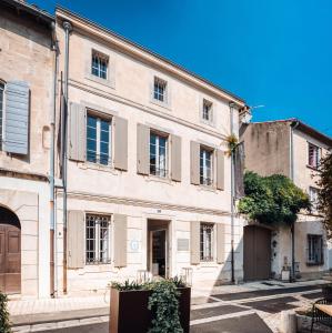 a large stone building in a street with trees at La Maison du Village in Saint-Rémy-de-Provence