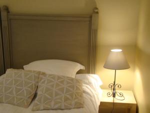 a bed with a white pillow and a lamp at L'Annexe Apparthôtel du 8, 3 étoiles in Besançon