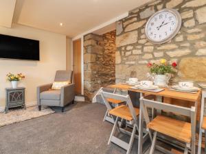 a dining room with a table and a clock on the wall at Folly Cottage in Settle