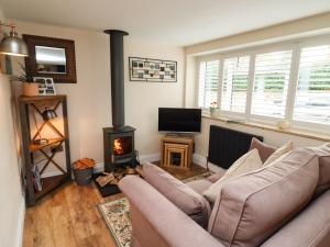 a living room with a couch and a wood stove at Thelwall Cottage in Banbury