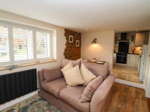 a living room with a couch and a kitchen at Thelwall Cottage in Banbury