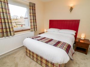 a bedroom with a bed with a red headboard and a window at Keartons - Buttertubs in Richmond