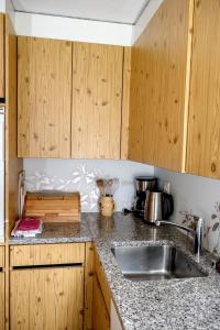 a kitchen with a sink and wooden cabinets at Schweiz ,Lenk Ferienwohnung,Kinderfreundl,Seniorenfreundlich in Lenk