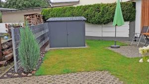 a garden with a gray shed in the yard at Ferienhaus "Brigitte" Objekt ID 12053-4 in Waren