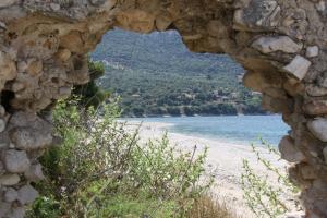 a view of a beach through a stone window at Asteri Apartments Mytikas 2-Bedroom Seaview Courtyard in Mitika