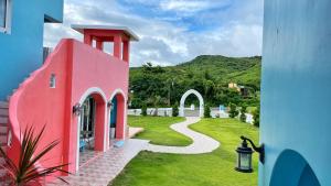 a pink house with a path in the grass at Wonderful Kenting Hostel in Eluan