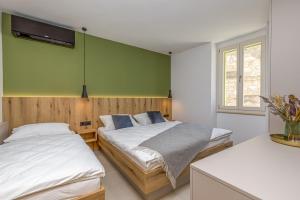 een slaapkamer met 2 bedden en een groene muur bij Casa Maslina in Vrsar